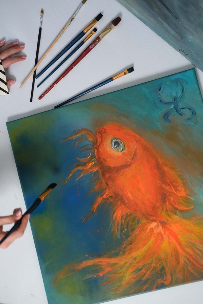 artist personal branding photography idea, paint brushes and a panting of a goldfish