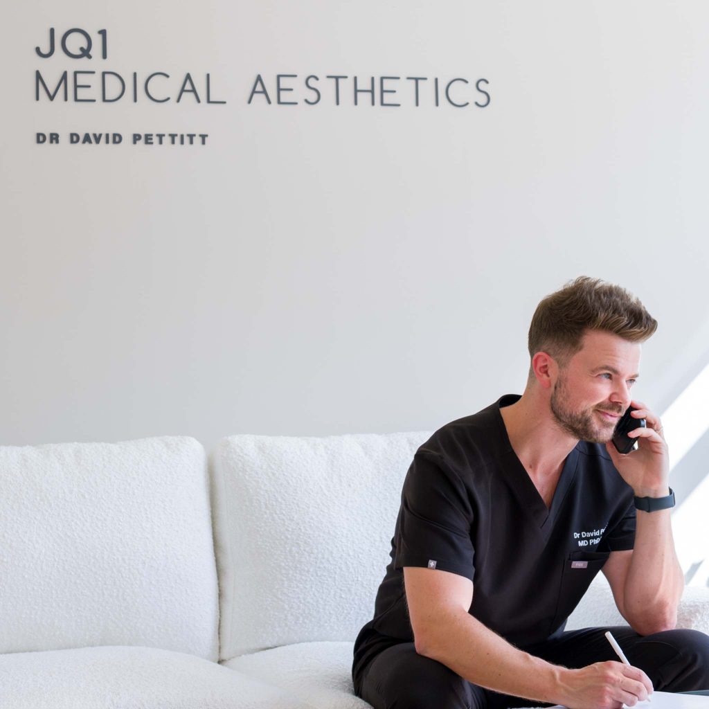 aesthetic doctor having a phone consultation with a client, smiling. Branding photography for a Birmingham aesthetic clinic